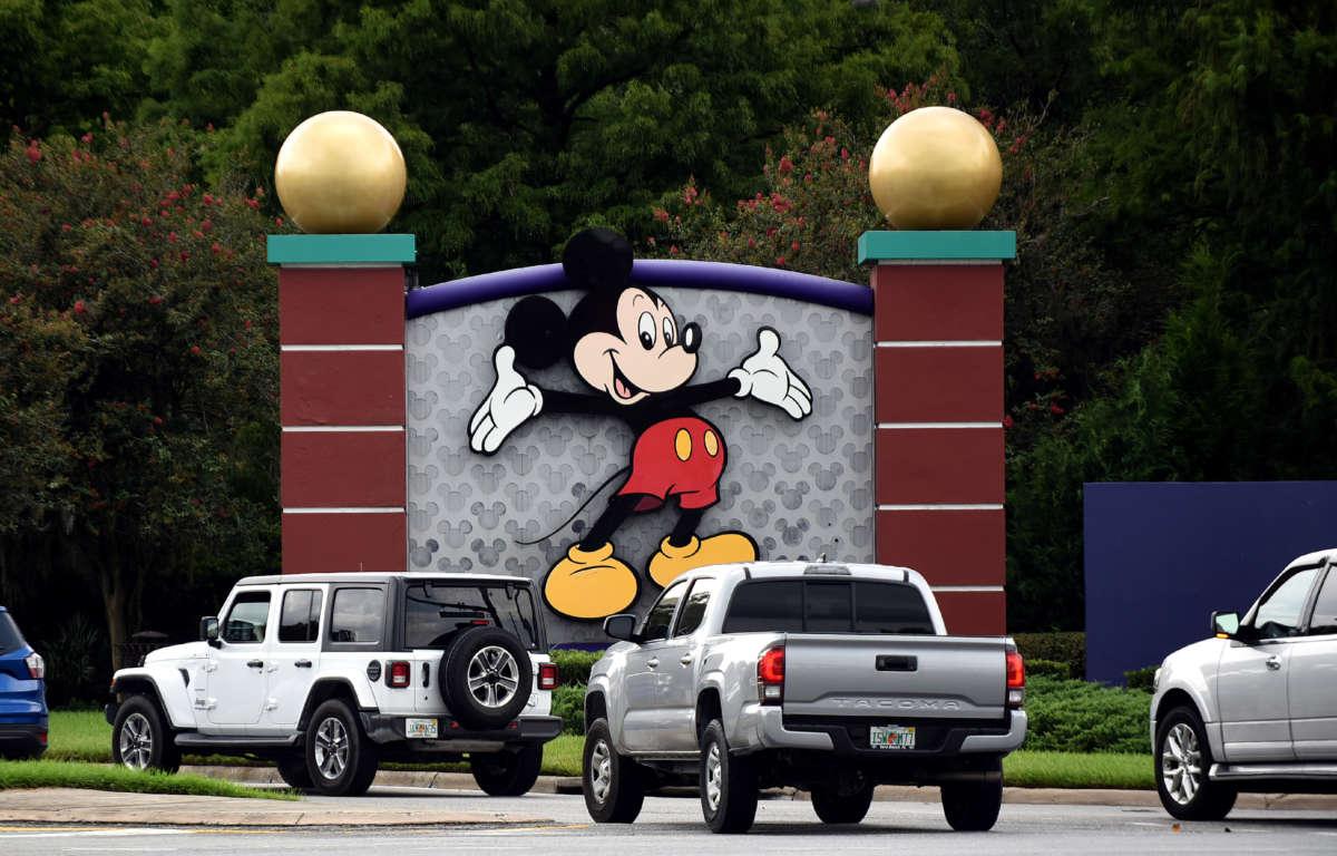 Cars drive past a sign featuring Mickey Mouse at the entrance to Walt Disney World in Lake Buena Vista, Florida, on July 11, 2020.