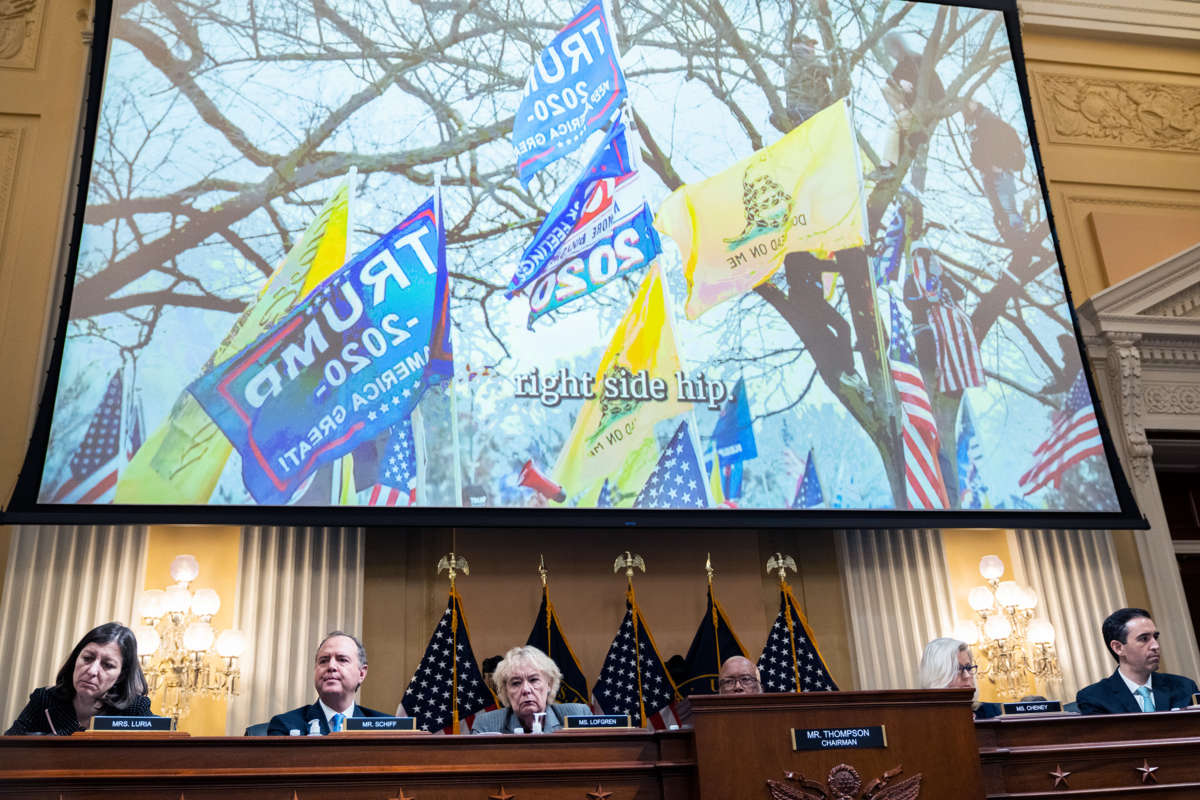 Trump and "don't tread on me" flags are seen waving in footage of the January 6 US Capitol riots, being played on a large screen during hearings