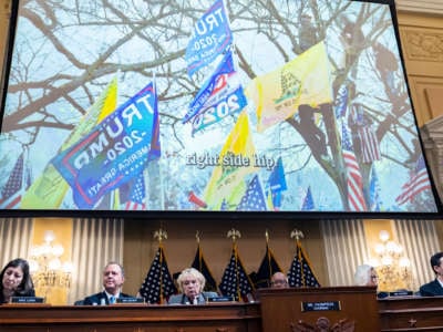 Trump and "don't tread on me" flags are seen waving in footage of the January 6 US Capitol riots, being played on a large screen during hearings