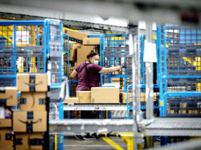 A worker sorts out parcels in the outbound dock at Amazon fulfillment center in Eastvale, California on Tuesday, Aug. 31, 2021.