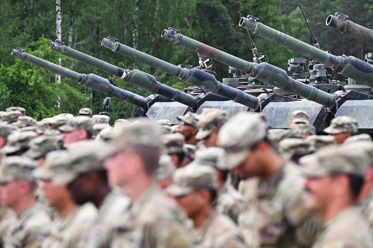 Soldiers stand in front of tanks