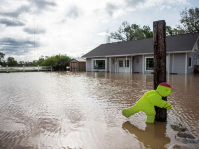 a partially submerged home is seen behind a sign indicating the presence of playing children