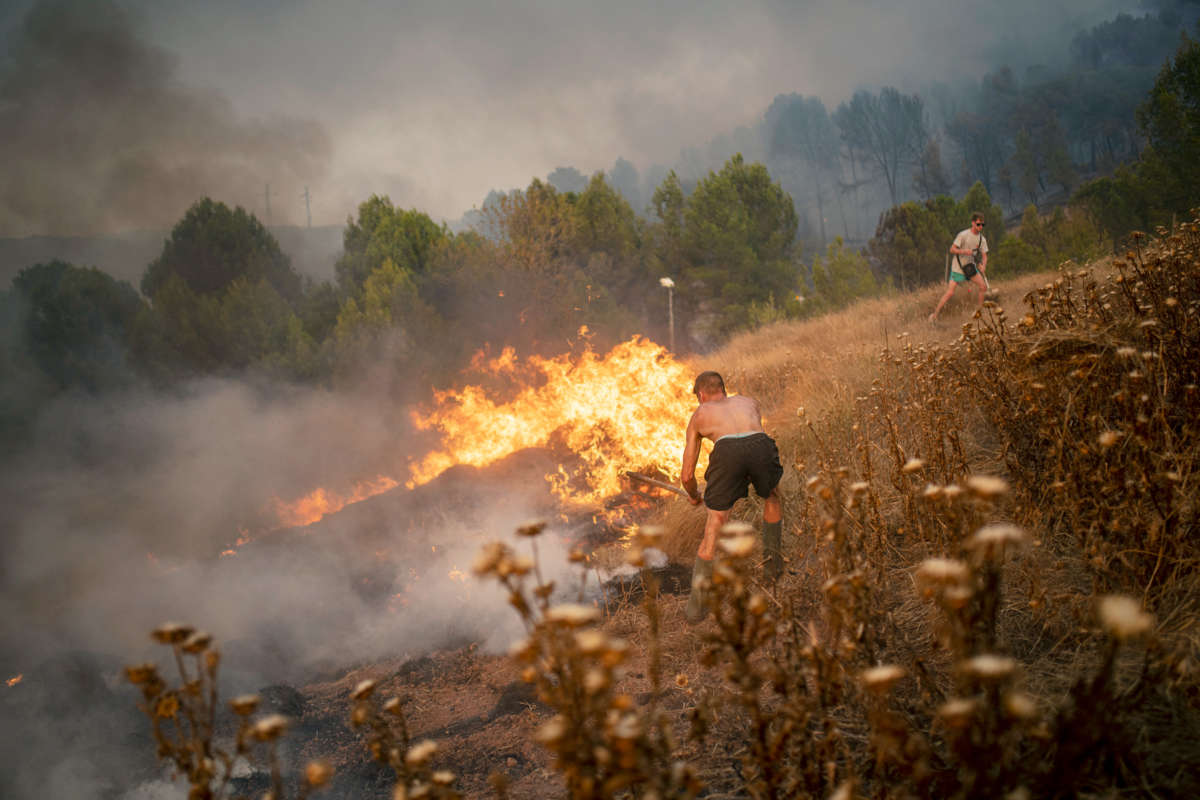 A shirtless man tries to fight a bushfire