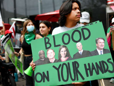 An abortion rights activist holds a sign depicting Supreme Court Justices Clarence Thomas, Samuel A. Alito, Jr., Amy Coney Barrett, Neil M. Gorsuch and Brett M. Kavanaugh during a demonstration outside a Planned Parenthood clinic as they safeguard the clinic from a possible protest by a far right group on July 16, 2022, in Santa Monica, California.