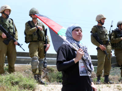 Manal Tamimi protests against settler-only roads in 2013 in Nabi Saleh, Palestine. The Israeli military denies Palestinians free use of these roads that are built on stolen land. 