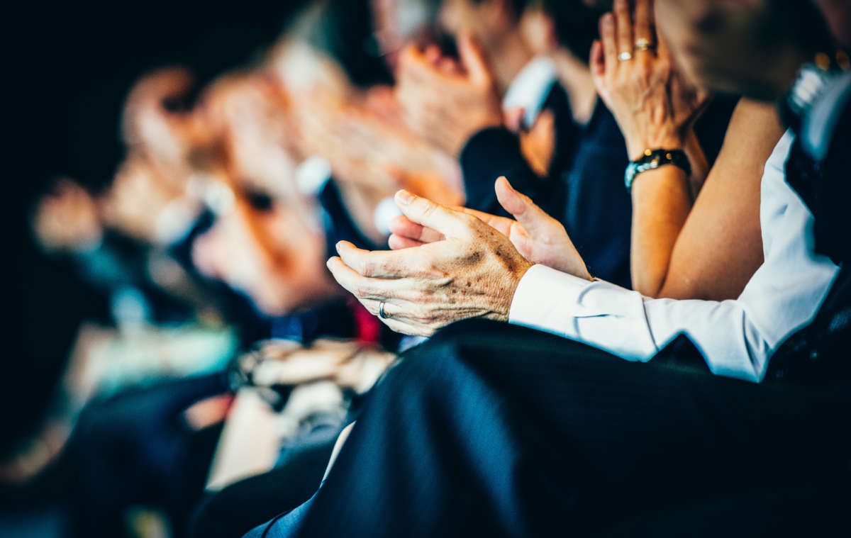 Business people clap at seminar, focus on hands.