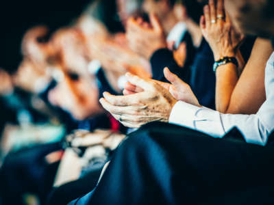 Business people clap at seminar, focus on hands.