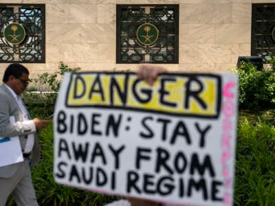 A human rights activist holds a sign protesting Saudi Arabia during an event to rename the street outside the Embassy of the Kingdom of Saudi Arabia to Jamal Khashoggi Way on June 15, 2022, in Washington, D.C. The event comes as President Biden announced his trip to Saudi Arabia July 11.