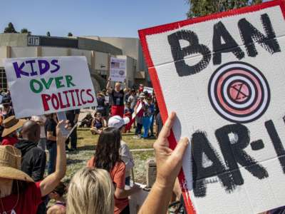 Prostestors hold signs that read "Ban AR-15s" and "Kids Over Politics"