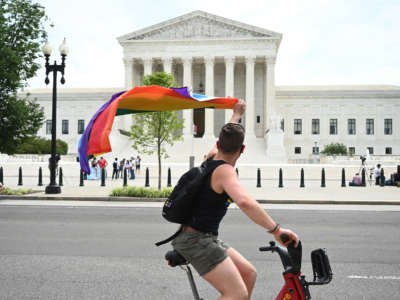 A man waves a rainbow flag as he rides by the U.S. Supreme Court on June 15, 2020, in Washington, D.C.