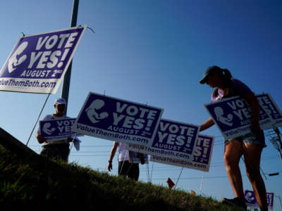 Supporters of the Vote Yes to a Constitutional Amendment on Abortion remove signs along 135th Street on August 1, 2022, in Olathe, Kansas.