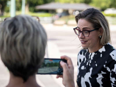 Sen. Kyrsten Sinema reacts to a journalist's question about whether she opposes closing the carried interest loophole that currently is part of the Democrats' $740 billion reconciliation bill, as she arrives at the U.S. Capitol for a vote on August 3, 2022, in Washington, D.C.