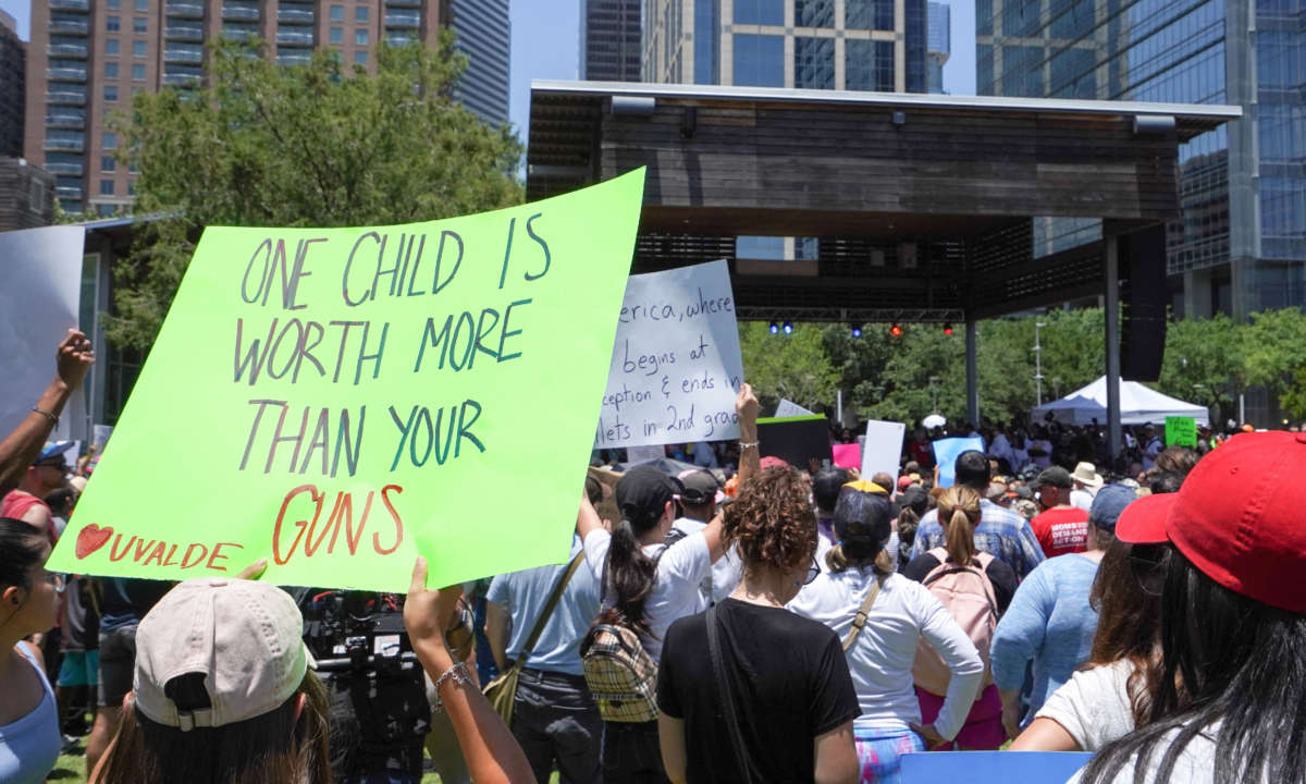 A sign reading 'One Child is Worth More than your Guns' is raised as demonstrators against the National Rifle Association (NRA) listen to Texas Democratic gubernatorial candidate Beto O'Rourke at Discovery Green across from the NRA Annual Meeting at the George R. Brown Convention Center, on May 27, 2022, in Houston, Texas.