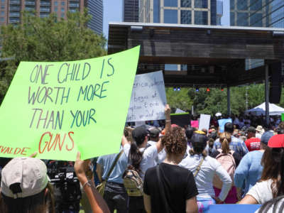 A sign reading 'One Child is Worth More than your Guns' is raised as demonstrators against the National Rifle Association (NRA) listen to Texas Democratic gubernatorial candidate Beto O'Rourke at Discovery Green across from the NRA Annual Meeting at the George R. Brown Convention Center, on May 27, 2022, in Houston, Texas.