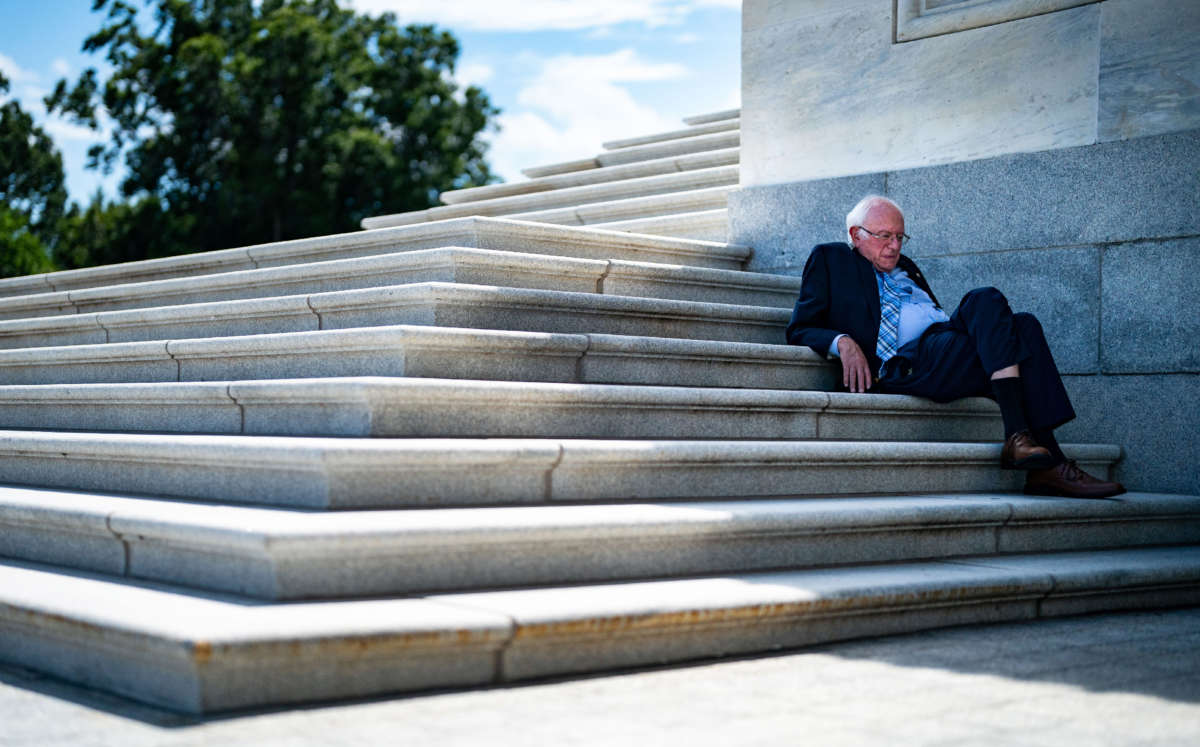 Sen. Bernie Sanders sits in the shade on the steps of the Senate as the Senate proceeds through a series of amendment votes on the Inflation Reduct Act at the U.S. Capitol on August 7, 2022, in Washington, D.C.