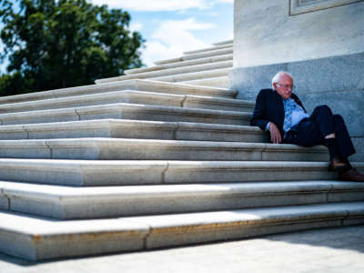 Sen. Bernie Sanders sits in the shade on the steps of the Senate as the Senate proceeds through a series of amendment votes on the Inflation Reduct Act at the U.S. Capitol on August 7, 2022, in Washington, D.C.