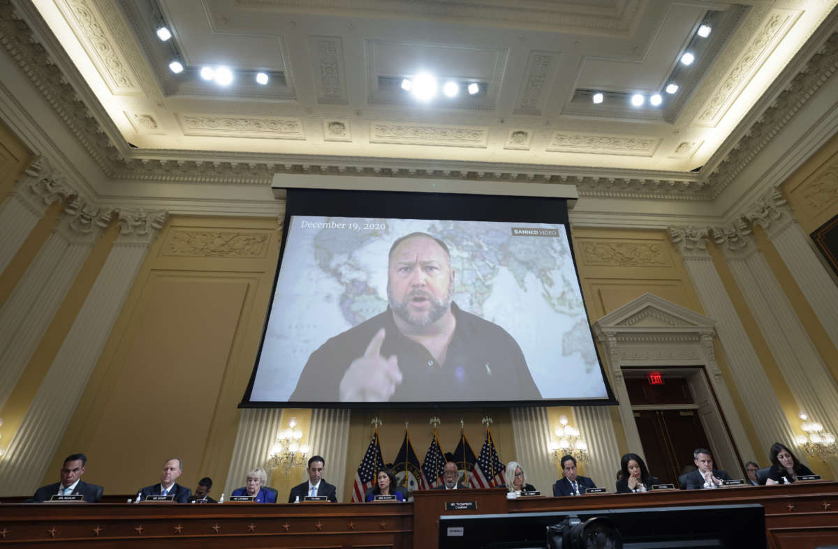 Far right radio show host Alex Jones appears on a video screen during videotaped testimony above members of the Select Committee to Investigate the January 6th Attack on the U.S. Capitol during the seventh hearing on the January 6th investigation in the Cannon House Office Building on July 12, 2022, in Washington, D.C.