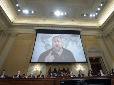 Far right radio show host Alex Jones appears on a video screen during videotaped testimony above members of the Select Committee to Investigate the January 6th Attack on the U.S. Capitol during the seventh hearing on the January 6th investigation in the Cannon House Office Building on July 12, 2022, in Washington, D.C.
