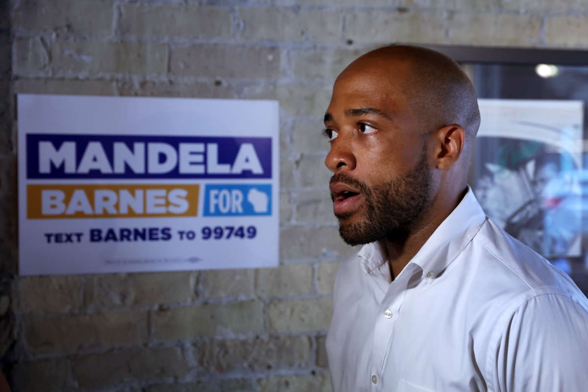 Mandela Barnes walks by a campaign poster bearing his name