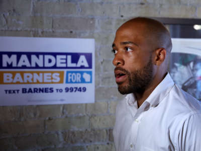 Mandela Barnes walks by a campaign poster bearing his name