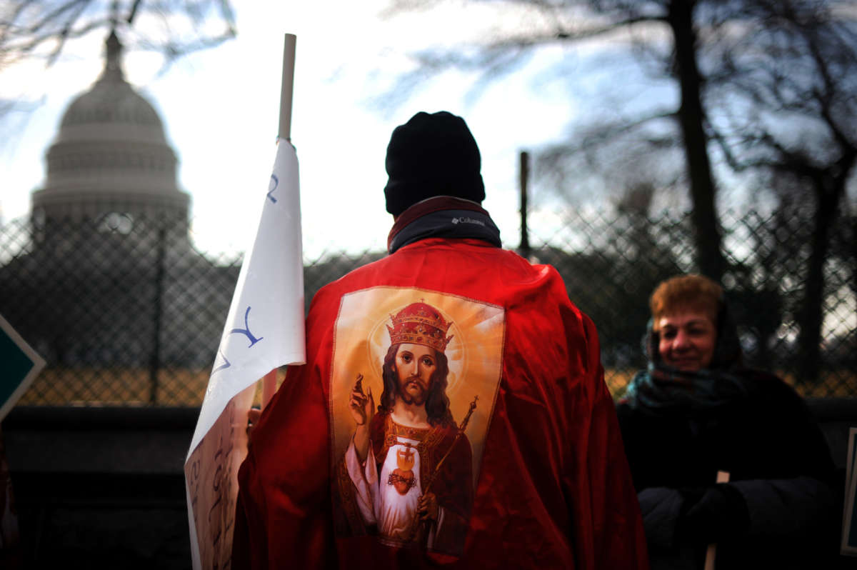 An anti-abortion protester faces away from us, looking at U.S. Capitol, and wears an image of Christ on their back.