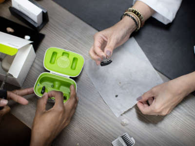 Janine Ramirez, Hearing Aid Specialist with the Hear Again America co., helps a patient with her hearing aid on October 20, 2021, in Fort Lauderdale, Florida.