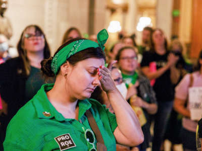 A protester in green rests her forehead in her hands