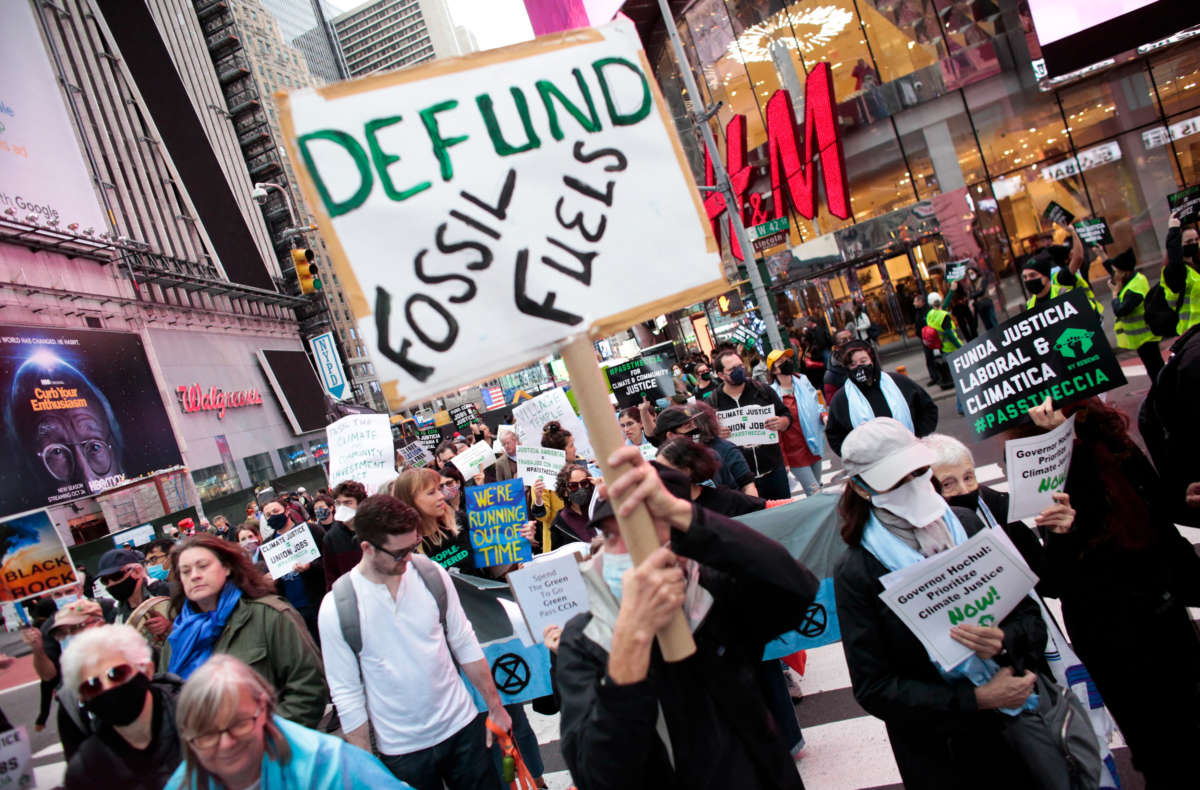 A sign reads 'Defund Fossil Fuels' at a climate crisis march in Times Square, New York