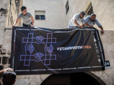 Activists hang a poster at the entrance to al-Haq Human Rights Organization, after it was raided and shut down by Israeli Military forces, on August 18, 2022, in Ramallah, Palestine.