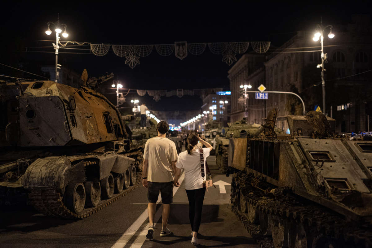 A couple walks by burnt-out Russian military vehicles displayed in the downtown area on August 22, 2022, in Kyiv, Ukraine.