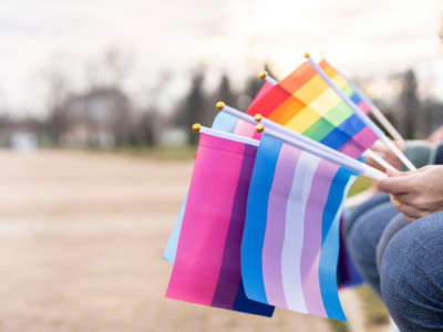 People sit with LGBTQ pride flags in hands