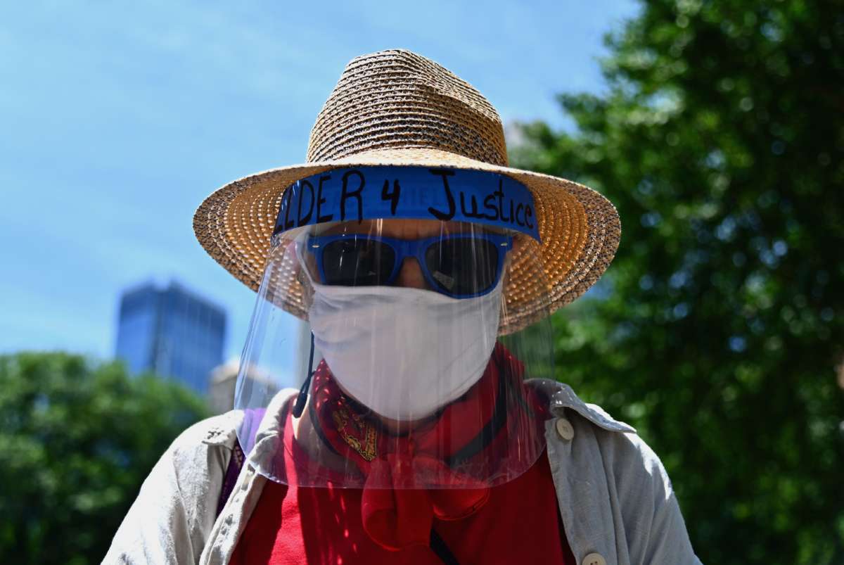 An elderly protestor wears a face mask with a sign during a rally for defunding the New York Police Department (NYPD) outside City Hall on June 24, 2020, in New York City.