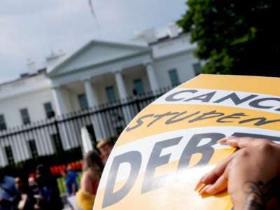 An activist holds a cancel student debt sign as they gather to rally in front of the White House in Washington, D.C., on August 25, 2022.