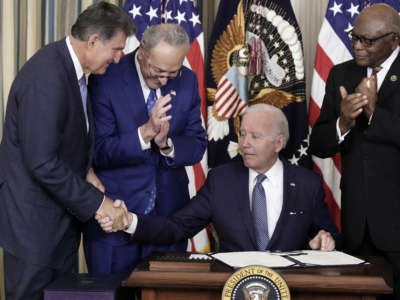 El presidente Joe Biden le da la mano al senador Joe Manchin después de firmar la Ley de Reducción de la Inflación junto con el líder de la mayoría del Senado, Charles Schumer, y el látigo de la mayoría de la Cámara, James Clyburn, en el comedor estatal de la Casa Blanca, el 16 de agosto de 2022, en Washington, DC