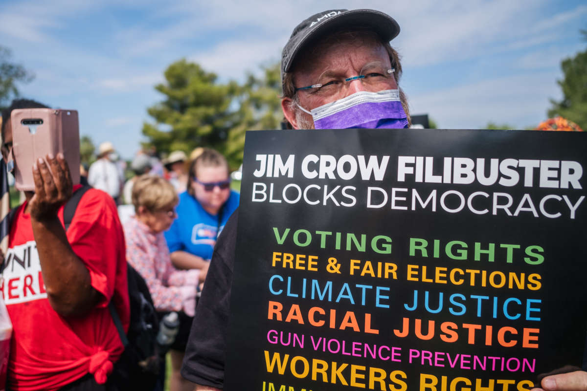 A man displays a sign during a demonstration to oppose the Senate filibuster on July 26, 2021 in Phoenix, Arizona, demanding Sen. Kyrsten Sinema (D-AZ) help put an end to the filibuster.