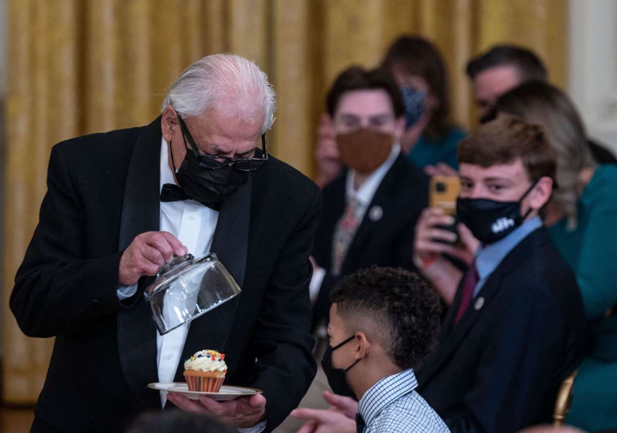 A White House butler delivers a birthday cupcake to a child who helps care for a US veteran during an event to honor children in military and veteran caregiving families at the White House in Washington, D.C on November 10, 2021.
