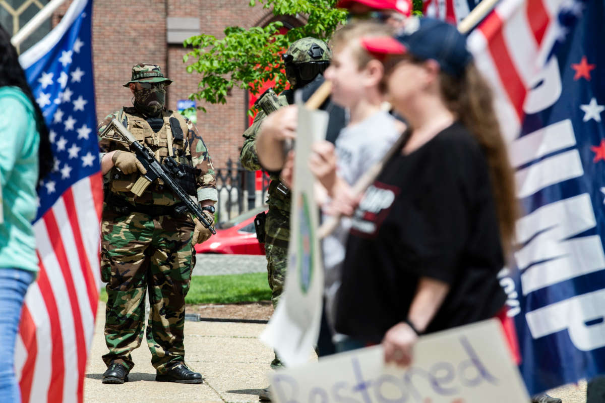 Armed members of the New England Minutemen militia group watch rally goers march with Trump flags, during the anti-mask and anti-vaccine "World Wide Rally for Freedom" at the statehouse in Concord, New Hampshire, on May 15, 2021.