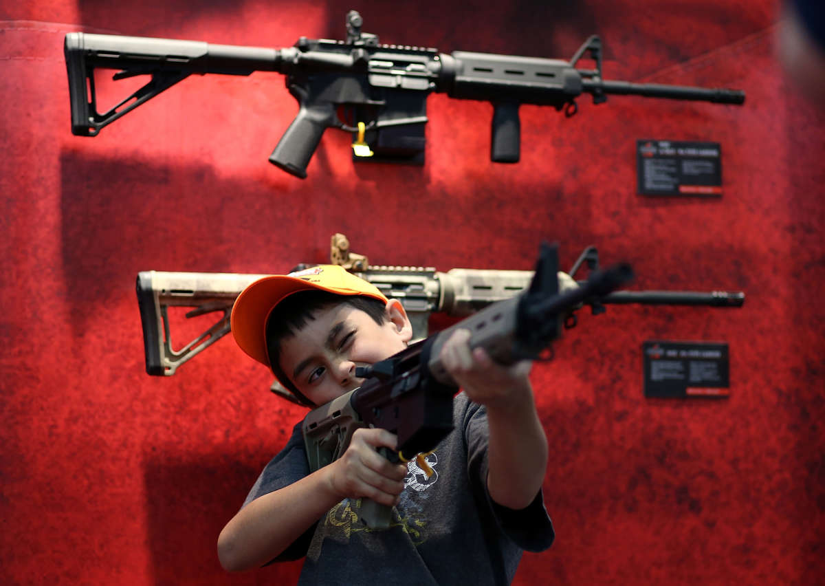 A young attendee inspects an assault rifle during the 2013 NRA Annual Meeting and Exhibits at the George R. Brown Convention Center on May 4, 2013, in Houston, Texas.