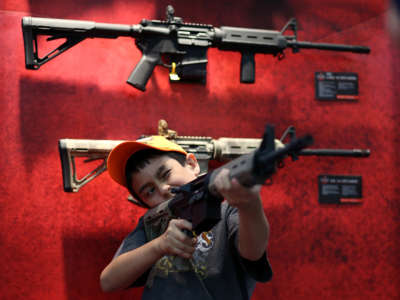 A young attendee inspects an assault rifle during the 2013 NRA Annual Meeting and Exhibits at the George R. Brown Convention Center on May 4, 2013, in Houston, Texas.