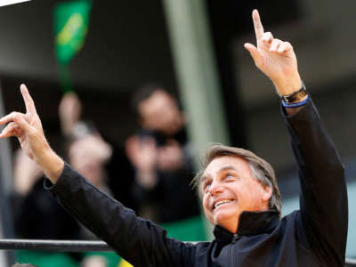 Brazil's president and presidential candidate Jair Bolsonaro points upward with both hands during a rally