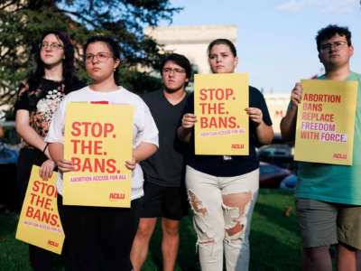 People hold signs reading "STOP THE BANS; ABORTION ACCESS FOR ALL" during a protest