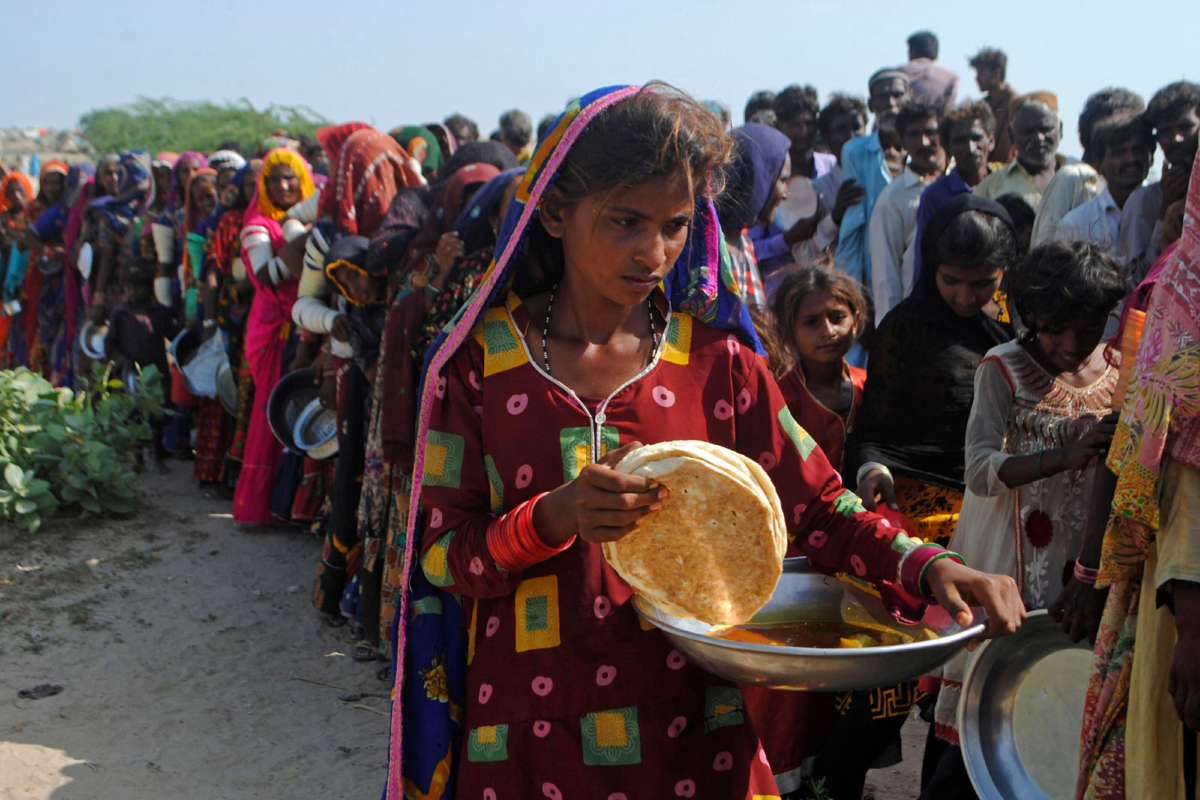Internally displaced people gather to receive food near their makeshift camp in the flood-hit Chachro Tehsil in Sindh, Pakistan, on September 19, 2022.