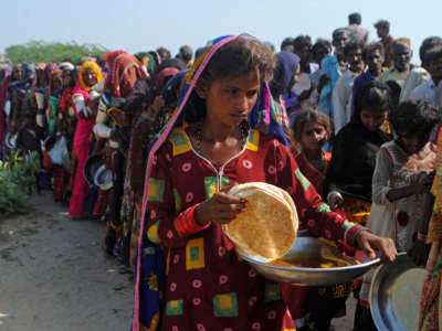 Internally displaced people gather to receive food near their makeshift camp in the flood-hit Chachro Tehsil in Sindh, Pakistan, on September 19, 2022.