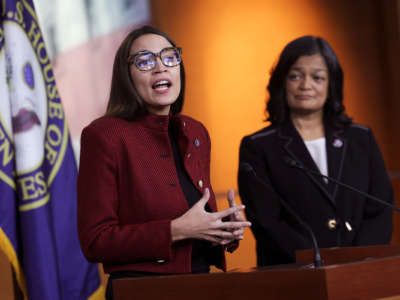 AOC speaks at a podium in a way that is visually reminiscent of a rebuke