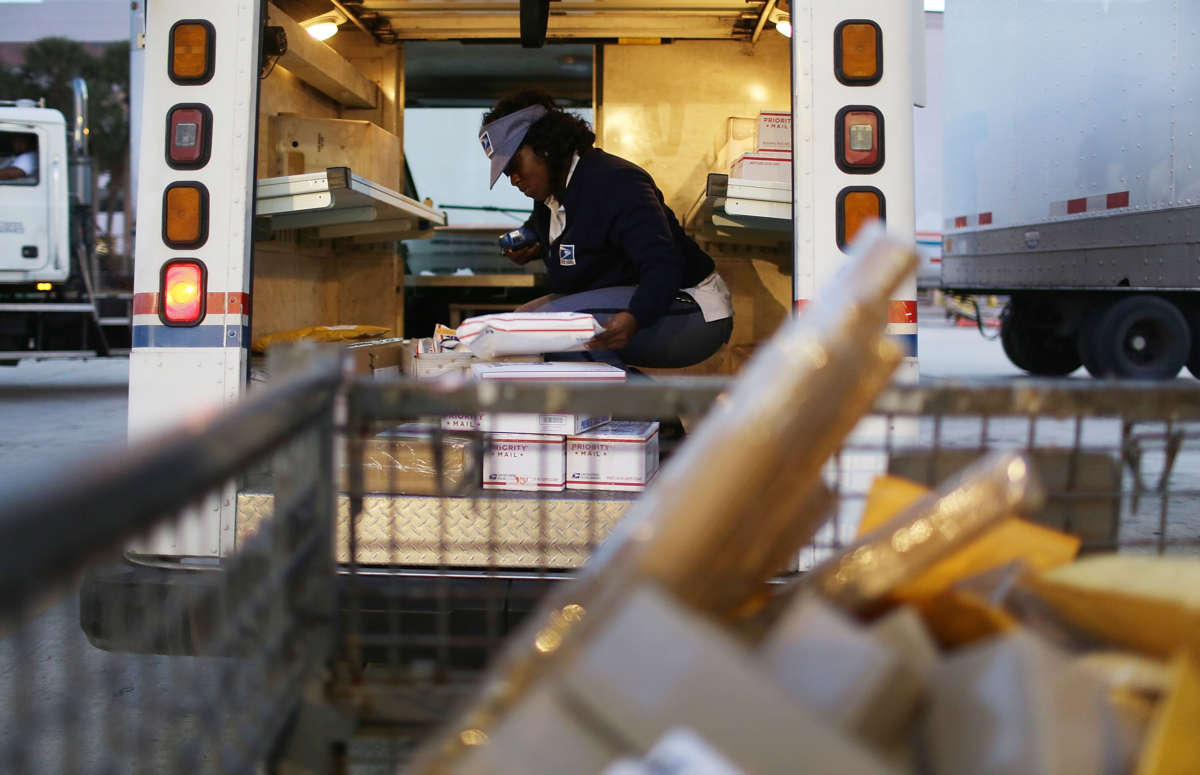 A United States Postal Service mail handler works to unload her mail truck at the Processing and Distribution Center on December 14, 2015, in Miami, Florida.