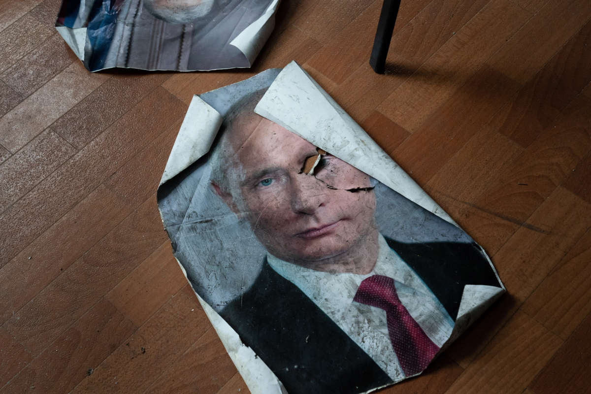 A dirtied and tread-upon portrait of Vladimir Putin is seen on the ground
