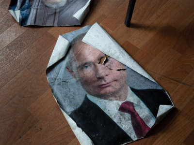 A dirtied and tread-upon portrait of Vladimir Putin is seen on the ground