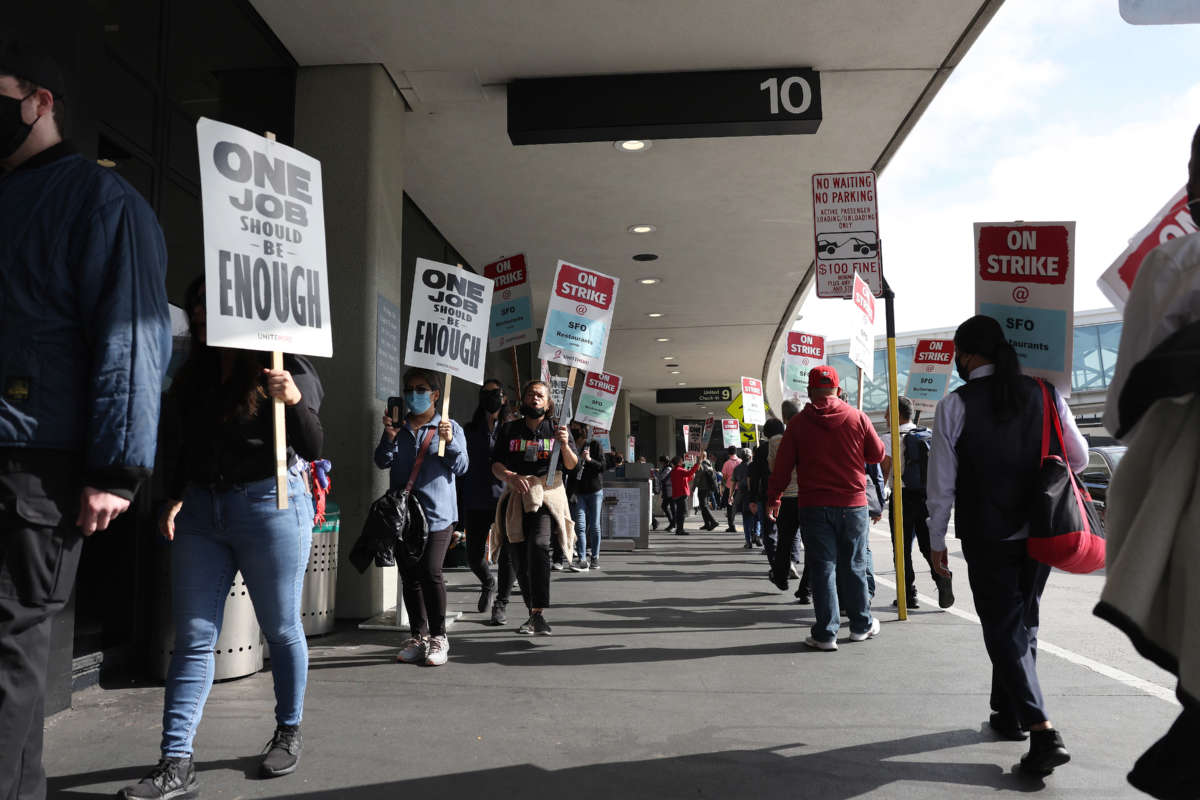 San Francisco International Airport food service workers carry signs as they strike outside of a terminal at the airport on September 26, 2022, in San Francisco, California.