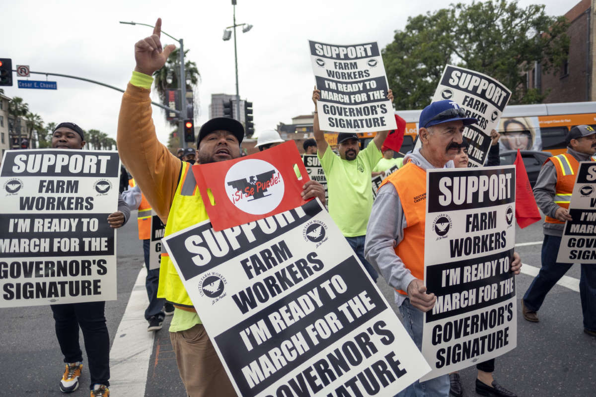 People hold signs during a demonstration organized by the UFW Foundation at Cesar E. Chavez Avenue and Alameda Street in Los Angeles, California, to support AB 2183, on March 31, 2022.