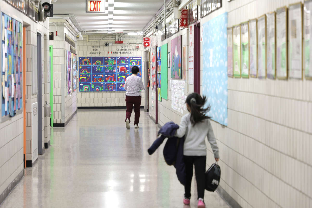 Principal Alice Hom walks down a hallway followed by a student at Yung Wing School P.S. 124 on April 11, 2022, in New York City.